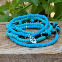 Very pretty 5 stack bracelets of blue and green glass beads with a bear paw charm. This bracelet is stretchable.